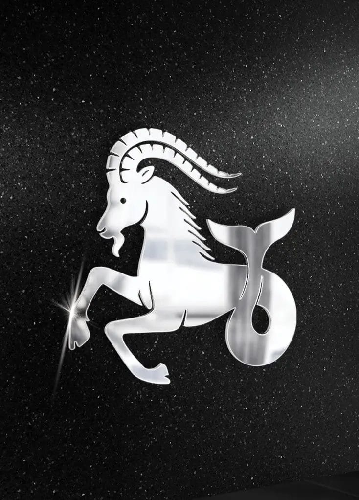 Stalowa figura Koziorożca, znaku zodiaku, na tle nagrobka